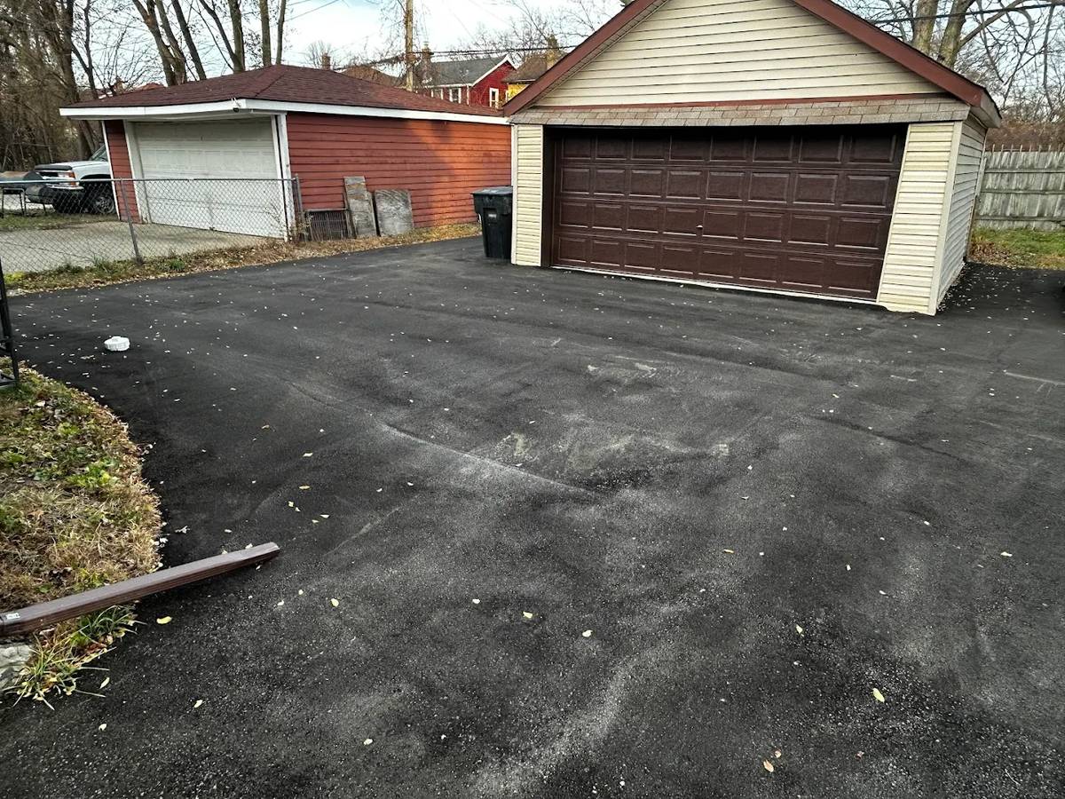 New asphalt driveway up to an attached garage